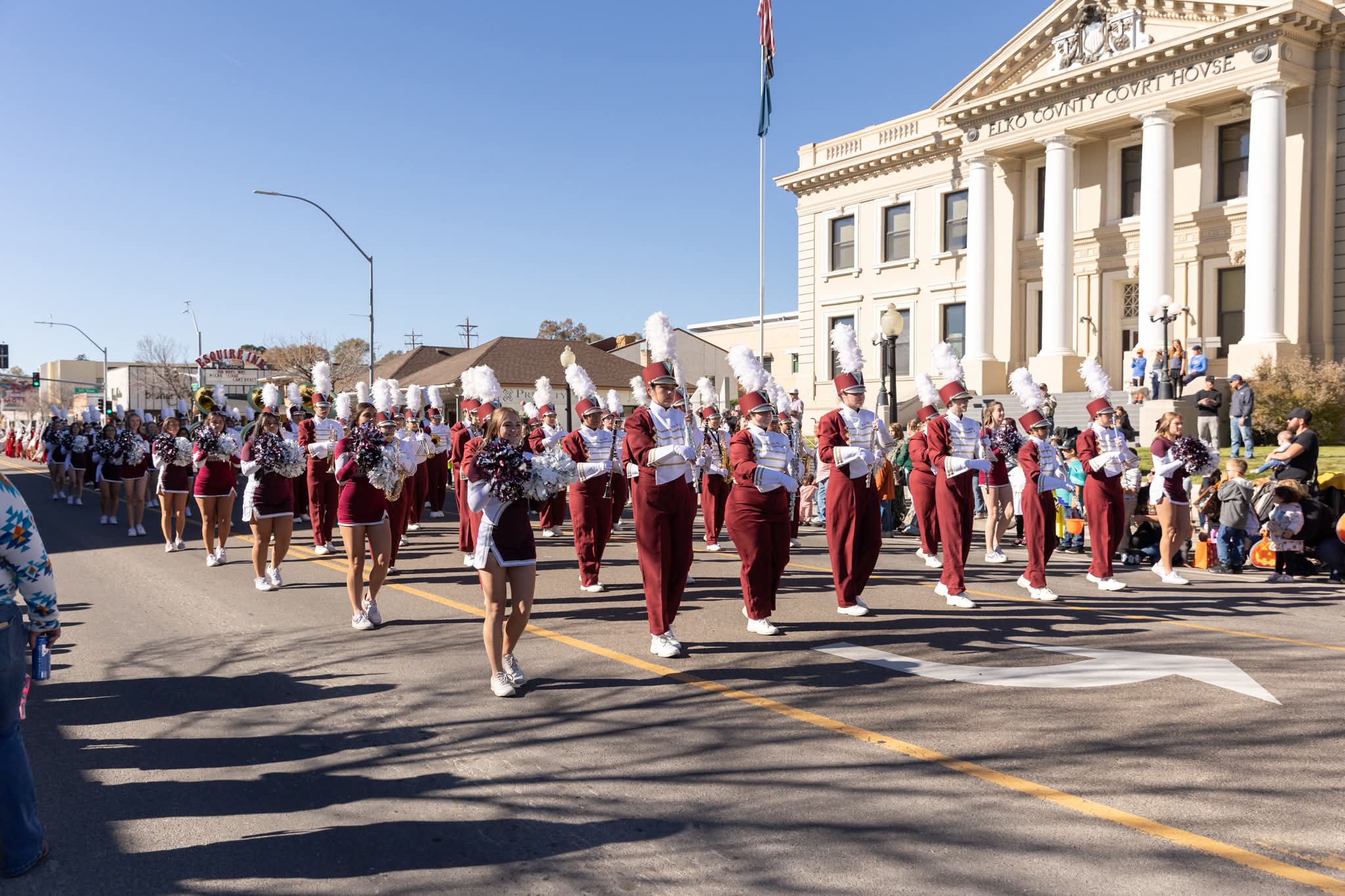 Marching band and cheerleaders passing the Elko County Courthouse during the Nevada Day Parade